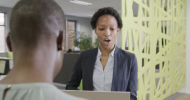 İki Afro-Amerikalı iş kadını iş hakkında konuşuyor ve ofiste dizüstü bilgisayarlarını yavaş çekimde kullanıyorlar. İş, takım çalışması, kapsayıcılık ve iletişim.
