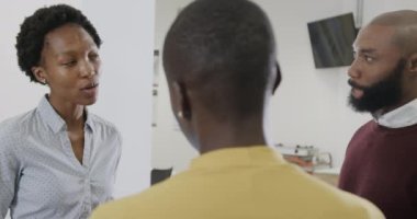 Mutlu Afro-Amerikan erkek ve bayan iş arkadaşları ofiste tartışıyor, ağır çekimde. İş, takım çalışması, kapsayıcılık ve iletişim.