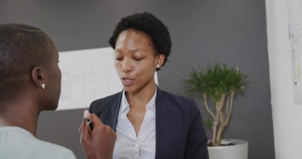 アフリカ系アメリカ人のクリエイティブビジネス女性2人がオフィスで議論中で ゆっくりと動きます ビジネス チームワーク 包括性 コミュニケーション — ストック動画