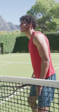 Güneşli bir günde tenis raketli mutlu melez adamın dikey videosu. Boş zaman, spor ve aktivite.