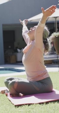 Kafkasyalı kadının yoga yaptığı, bahçede meditasyon yaptığı, yavaş çekim yaptığı dikey bir video. Kaliteli zaman, emeklilik, spor ve sağlık hizmetleri.