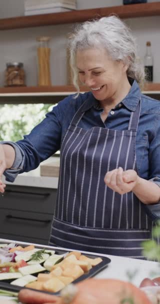 キッチンでのシニア白人女性調味料野菜の垂直ビデオ スローモーション 国内生活 ライフスタイルと料理 — ストック動画