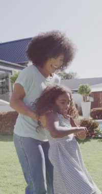 Mutlu çift ırklı anne ve kız bahçede oynuyor ve sarılıyor, ağır çekimde. Evde, evde ve ailede kaliteli zaman geçirmek.