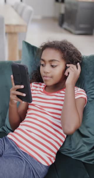 Pionowe Wideo Szczęśliwej Dwurasowej Dziewczyny Używającej Słuchawek Smartfona Zwolnione Tempo — Wideo stockowe