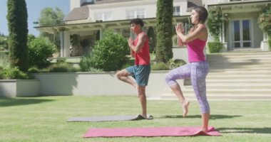 Yoga yapan ve güneşli bir günde bahçede poz veren odaklanmış çift. Boş zaman, sağlık ve etkinlik.