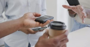 Afro-Amerikalı bir kadının kahvesini akıllı telefondan ısmarlaması, ağır çekimde. Yerel iş, teknoloji, kahve ve yemek servisi..