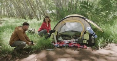 Mutlu Afro-Amerikan çifti ormanda çadır kuruyor, ağır çekimde. Kaliteli zaman geçirmek, yaşam tarzı, doğa, yürüyüş ve kamp..