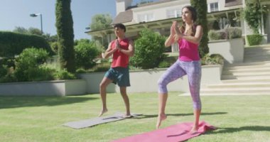 Yoga yapan ve güneşli bir günde bahçede poz veren odaklanmış çift. Boş zaman, sağlık ve etkinlik.