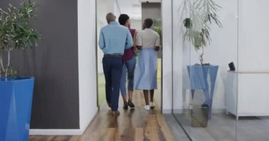 Afrika kökenli Amerikalı iş adamlarının ofis koridorunda ağır çekimde konuşmaları ve yürümeleri. İş, takım çalışması ve iletişim.