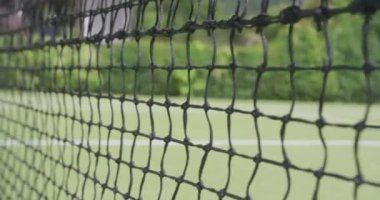 Güneşli bir günde bahçedeki tenis kortunda tenis ağı ve topu kapat. Spor, sağlık ve etkinlik.