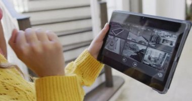 Çift ırklı kadın evde kamera arayüzü olan tablet kullanarak vakit geçiriyor. Boş zaman, teknoloji ve ev.