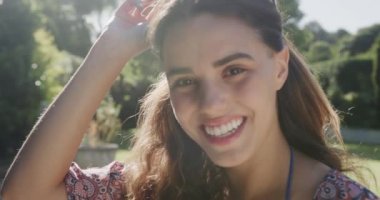 Güneşli bir günde bahçede güneş gözlüklü mutlu bir kadının portresi. Boş zaman ve tatil.