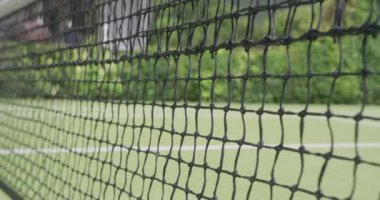 Güneşli bir günde bahçedeki tenis kortunda tenis ağı ve topu kapat. Spor, sağlık ve etkinlik.