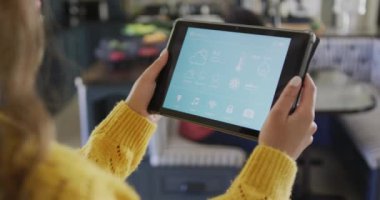 Çift ırklı kadın evde akıllı ev arayüzü olan tablet kullanarak zaman geçiriyor. Boş zaman, teknoloji ve ev.