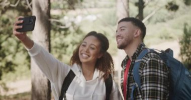 Mutlu Afro-Amerikan çifti akıllı telefon kullanıyor ve ormanda selfie çekiyor, yavaş çekim. Kaliteli zaman geçirmek, yaşam tarzı, doğa, yürüyüş ve kamp..