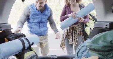 Mutlu Afro-Amerikan çifti bagajdan sırt çantalarını alıyor, ağır çekimde. Kaliteli zaman geçirmek, yaşam tarzı, doğa, yürüyüş ve kamp..