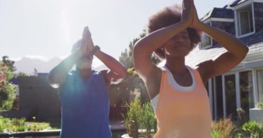 Afrika kökenli Amerikalı son sınıf çifti güneşli bahçede yoga yaparken meditasyon yapıyor. Karantina süresince evde tecrit altında kalmak.