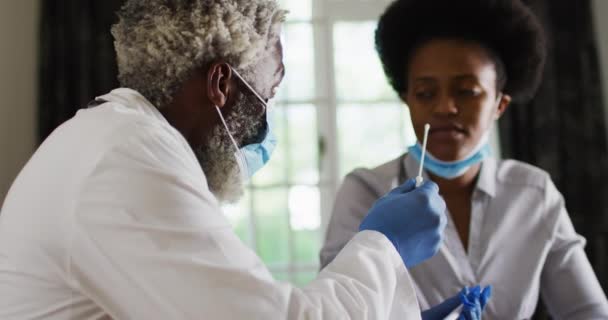 非洲裔美国高级男医生 戴着口罩 在家里为女性做眼镜蛇检查 隔离检疫期间单独呆在家里 — 图库视频影像