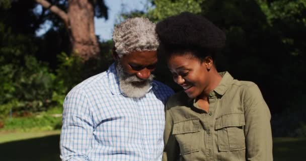 Улыбающаяся Африканская Старшая Пара Смотрит Смартфон Солнечном Саду Оставаться Дома — стоковое видео
