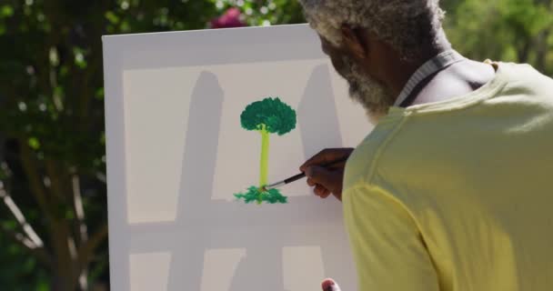 日当たりの良い庭のキャンバス上のシニアアフリカ系アメリカ人男性の絵 隔離されたまま家にいると — ストック動画