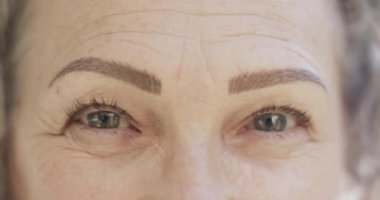 Kameraya gülümseyen, ağır çekimde gülümseyen mutlu beyaz kadın portresi. Emeklilik ve kıdemli yaşam tarzı, model değiştirilmemiş.