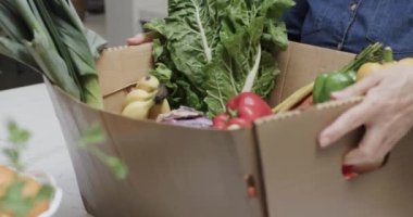 Mutfakta sebze ve meyve kutularını açan yaşlı beyaz kadının elleri, ağır çekimde. Yaşlı yaşam tarzı, beslenme ve sağlıklı beslenme, değişmemiş model..