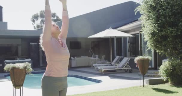 Feliz Mujer Caucásica Senior Haciendo Yoga Estirándose Junto Piscina Jardín — Vídeos de Stock