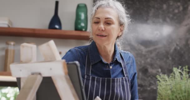 Ευτυχισμένη Ηλικιωμένη Καυκάσια Γυναίκα Που Χρησιμοποιεί Τάμπλετ Και Μαγειρεύει Στην — Αρχείο Βίντεο