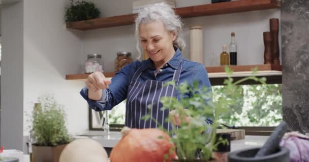 Χαμογελώντας Ηλικιωμένη Καυκάσια Γυναίκα Καρυκεύει Λαχανικά Στην Κουζίνα Αργή Κίνηση — Αρχείο Βίντεο