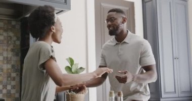 Mutlu Afro-Amerikan çifti ağır çekimde ktichen 'de el ele tutuşup dans ediyor. Evde kaliteli zaman geçirmek, neşe ve aşk.