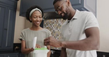 Mutlu Afro-Amerikan çifti ağır çekimde ktichen 'e yemek atıyorlar. Evde kaliteli zaman geçirmek, neşe ve yemek.