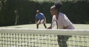 Kıdemli Afro-Amerikan çift tenis kortunda yavaş çekimde oynuyorlar. Emeklilik, aktif yaşam tarzı ve spor.