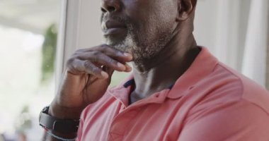 Düşünceli kıdemli Afrikalı Amerikalı adam çenesine ağır çekimde dokunuyor. Evde kaliteli zaman geçirmek, emeklilik ve umutsuzluk.