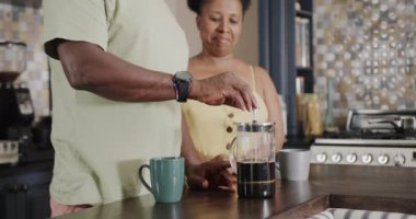 Happy senior african american couple preparing coffee in kitchen in slow motion. Spending quality time at home, retirement and drink.