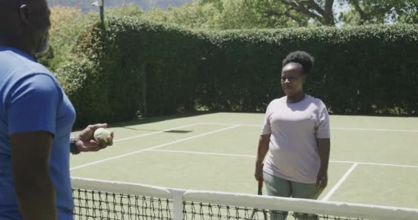Lykkelig Førsteårs Afroamerikansk Par Som Spiller Tennis Omfavner Tennisbanen Sakte – stockvideo
