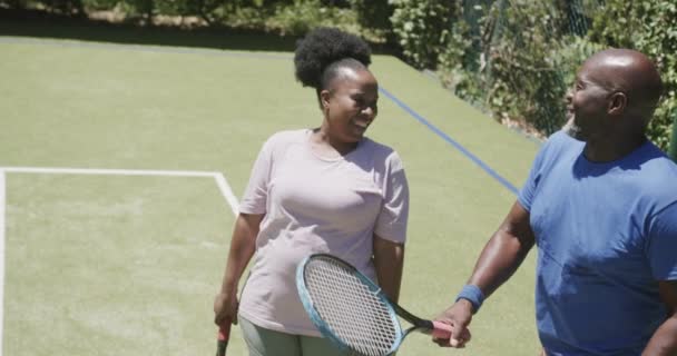 Szczęśliwa Starsza Afrykańska Para Chodząca Rakietami Tenisowymi Rozmawiająca Korcie Tenisowym — Wideo stockowe