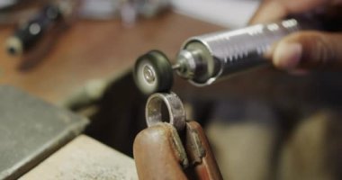 Yavaş çekimde atölyede el işi aletleri kullanarak yüzük şekillendiren melez kadın işçi. Mücevher, zanaat ve küçük işletmeler..