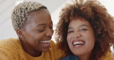 Oturma odasında yavaş çekimde görüntülü konuşma yapan mutlu lezbiyen kadın portresi. Kaliteli zaman geçirmek, neşe, video çağrısı ve aşk.