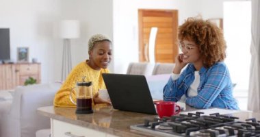 Yavaş çekimde konuşan ve dizüstü bilgisayar kullanan mutlu lezbiyen çift. Kaliteli zaman, eğlence, teknoloji ve aşk harcamak.