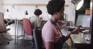 Afrika kökenli Amerikalı kadın işçi, mücevher stüdyosunda ağır çekimde yüzük tutuyor. Mücevher, zanaat ve küçük işletmeler..