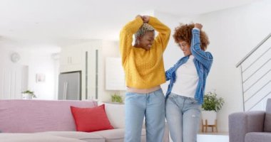 Oturma odasında yavaş çekimde dans eden mutlu lezbiyen çift. Kaliteli zaman geçirmek, neşe, eğlence ve aşk.