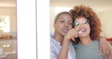 Mutlu lezbiyen kadın çift yavaş çekimde evlerinde pencereden konuşuyorlar ve bakıyorlar. Kaliteli zaman geçirmek, neşe ve aşk.