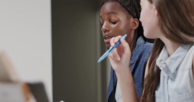 Bilgisayar kullanarak ve konuşarak evde ders çalışan farklı genç bayan arkadaşlar. Arkadaşlık, yaşam tarzı, eğitim ve çevrimiçi öğrenme.