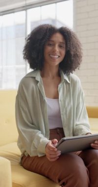 Ofiste tablet kullanan mutlu çift ırklı iş kadınının portresinin dikey videosu. İş, teknoloji ve güven.
