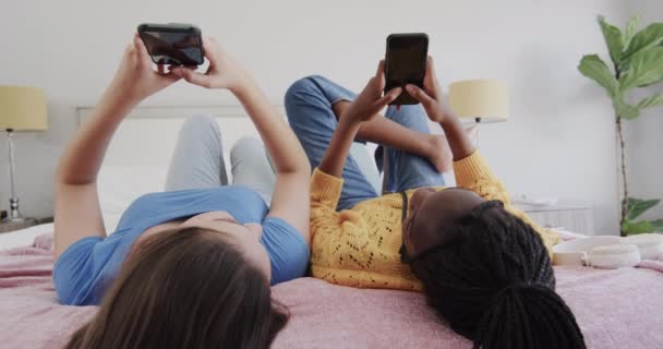 Szczęśliwe Zróżnicowane Nastolatki Leżące Plecach Łóżku Korzystające Smartfonów Mówiące Przyjaźń — Wideo stockowe