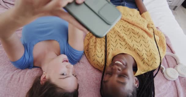 Boldog Sokszínű Tinédzser Női Barátok Fekszenek Hátukon Ágyon Okostelefonnal Szelfit — Stock videók