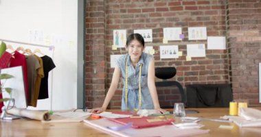 Moda tasarım stüdyosunda ağır çekimde çalışan mutlu Asyalı kadın tasarımcının portresi. Günlük ofis, iş ve yaratıcı iş.