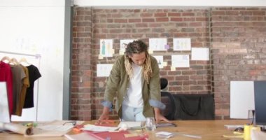 Moda tasarım stüdyosunda ağır çekimde tablet kullanan mutlu çift ırklı erkek tasarımcının portresi. Günlük ofis, iş ve yaratıcı iş.