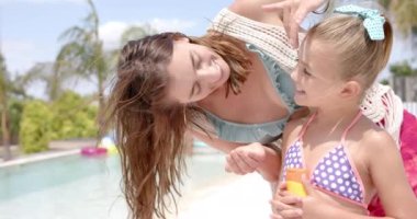 Mutlu beyaz anne yüzme havuzunda kızına krem sürüyor. Tatil, boş zaman, yaz ve aile.