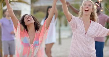 Kumsalda havai fişeklerle dans eden mutlu arkadaş grubu. Tatil, boş zaman, yaz ve arkadaşlık.